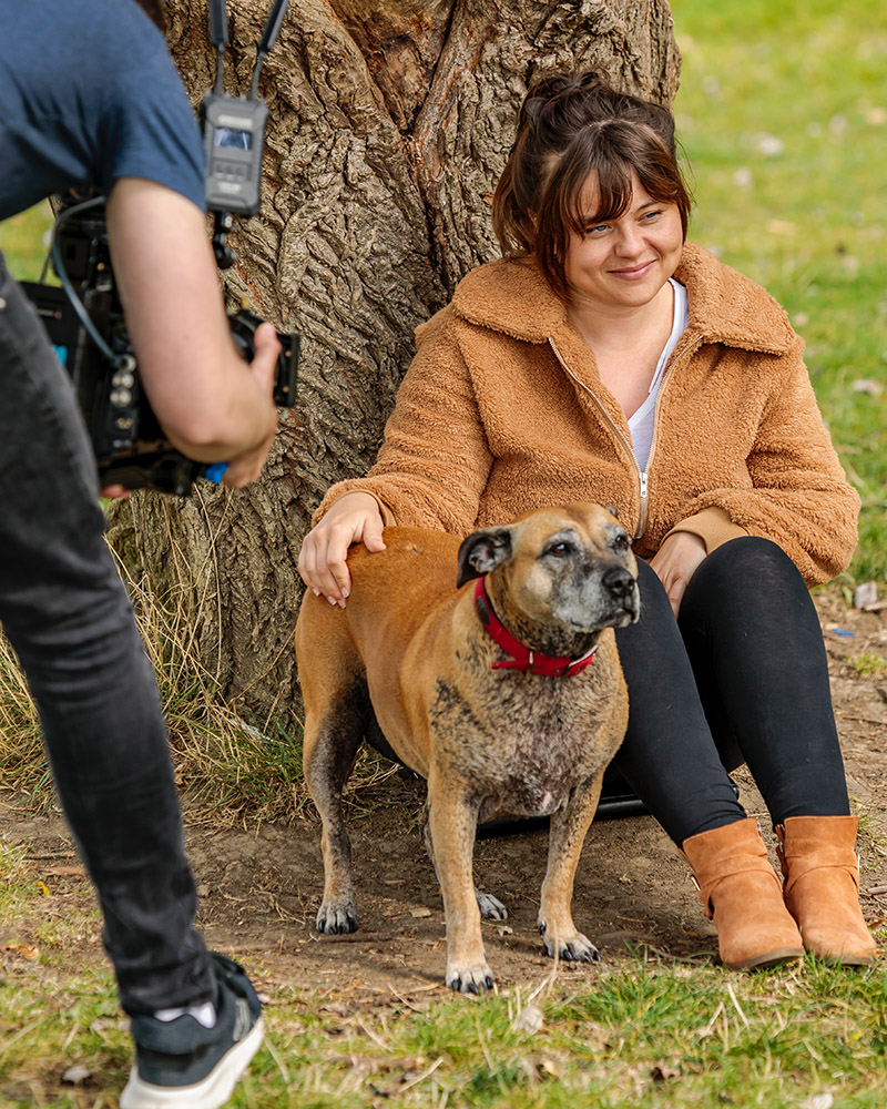 Girl being video sat by a tree with her dog